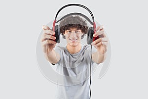 Young handsome smiling man, holding headphones in his hand and showing them to the camera before putting them on to listen to