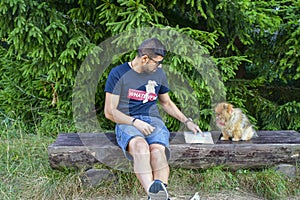 Young handsome smiling man  reading outdoor with a dog