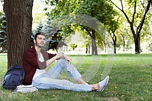 Young handsome man sitting on grass outdoors