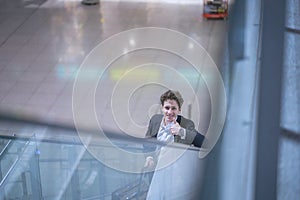 Young handsome smiling man in a suit on an escalator with thumb up