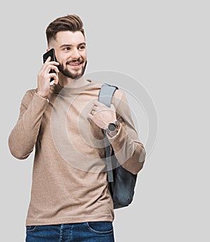 Young handsome smiling man talking on mobile phone. Student men using smartphone. Isolated closeup studio portrait, gray backgroun