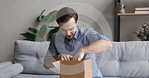 Young handsome smiling man unpacking small carton box.