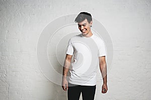 Young handsome smiling man wearing white blank t-shirt, horizontal studio portrait