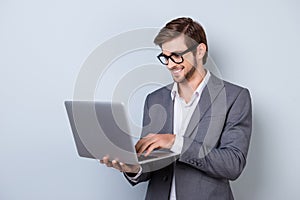 Young handsome smiling manager in suit holding laptop and chatting with his business colleagues