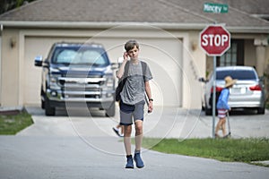 Young handsome smiling teenager boy with backpack happy going to school on sunny day