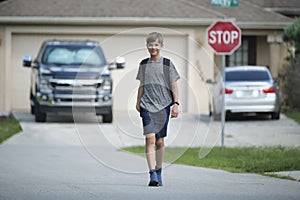 Young handsome smiling teenager boy with backpack happy going to school on sunny day