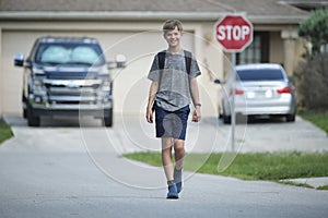 Young handsome smiling teenager boy with backpack happy going to school on sunny day