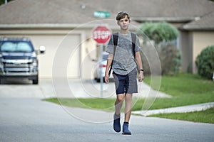 Young handsome smiling teenager boy with backpack happy going to school on sunny day