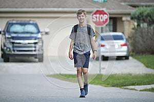Young handsome smiling teenager boy with backpack happy going to school on sunny day