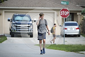 Young handsome smiling teenager boy with backpack happy going to school on sunny day