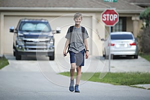 Young handsome smiling teenager boy with backpack happy going to school on sunny day