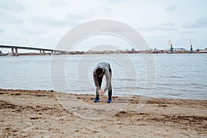 Young handsome sports man doing stretching before run at the beach