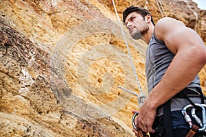 Young handsome sportsman getting ready to climb a cliff