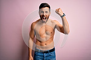 Young handsome strong man with beard shirtless standing over isolated pink background angry and mad raising fist frustrated and