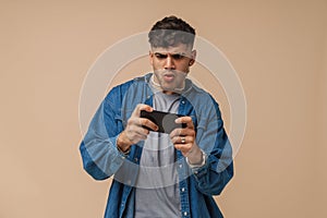 Young handsome stylish interested focused man playing mobile game