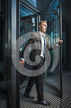 Young handsome successful stylish businessman near modern office