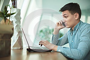 Young handsome surprised businessman has conversation on his smartphone and works in his laptop while waiting for lunch