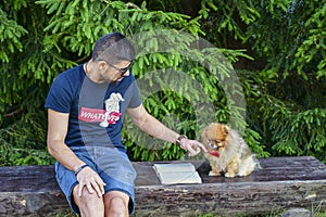 Young handsome smiling man  reading outdoor with a dog