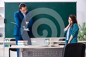 Young handsome teacher and female student in the classroom