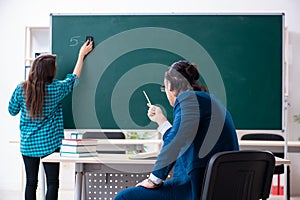 Young handsome teacher and female student in the classroom