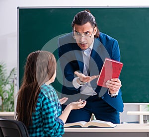 Young handsome teacher and female student in the classroom