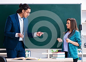 Young handsome teacher and female student in the classroom