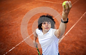 Young handsome tennis player with racket and ball prepares to serve at beginning of game or match.