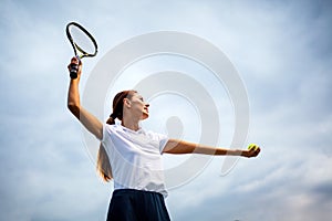 Young handsome tennis player with racket and ball prepares to serve at beginning of game or match.