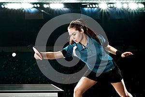 Young handsome woman tennis-player in play on black background. Action shot.