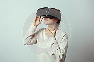 Young handsome woman wearing virtual headset. Excited Hipster using VR glasses. Empty studio wall background