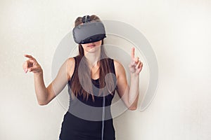Young handsome woman wearing virtual headset. Excited Hipster using VR glasses. Empty studio wall background.