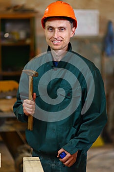 Young and handsome worker man holding a hammer