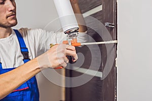 Young handyman installing door with an mounting foam in a room