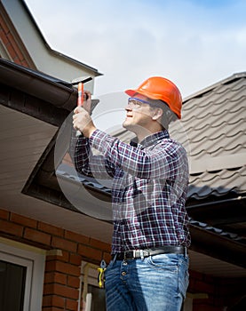 Young handyman repairing house roof with nails and hammer