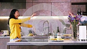 Young happy active family couple dancing laughing together preparing food at home, carefree joyful husband and wife having fun