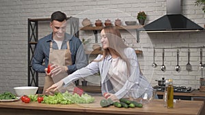 Young happy active family couple dancing laughing together preparing food at home, carefree joyful husband and wife having fun coo