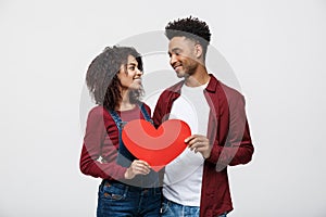 Young happy African American couple in love holding red paper heart.
