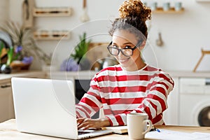 Young happy African American woman freelancer smiling at camera, enjoying remote work at home office