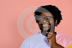 young happy african american man posing in the studio over pink background