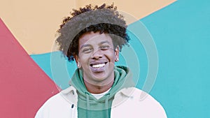 Young happy African American teen guy standing at colorful wall. Portrait