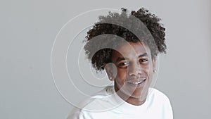 Young happy African American teen guy standing at grey wall. Portrait