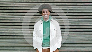 Young happy African American teen guy standing at wooden wall. Portrait