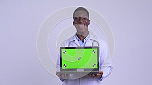 Young happy African man doctor showing laptop and looking surprised