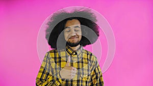 Young happy afro american man smiling while giving thumbs up on purple background. Concept of emotions