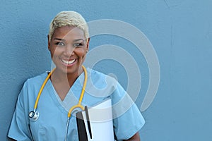 Young happy afro american nurse standing at hospital ward with clipboard and pen in hand. Smiling, looking at camera