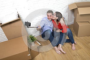 Young happy American couple sitting on floor taking selfie photo celebrating moving in new house or apartment