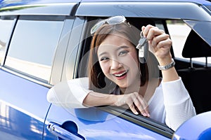 Young happy Asian car driver woman smiling and showing new car keys.