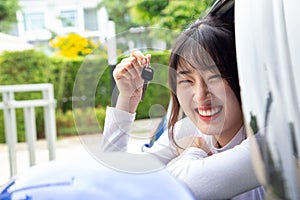 Young happy Asian car driver woman smiling and showing new car keys.