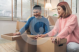 Young happy Asian couple moving to their new home, open boxes to check old objects from old home. Lifestyle couple move new home