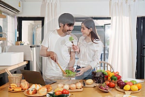 Young happy asian couple preparing healthy meal in kitchen at home. Food and healthy lifestyle concept.